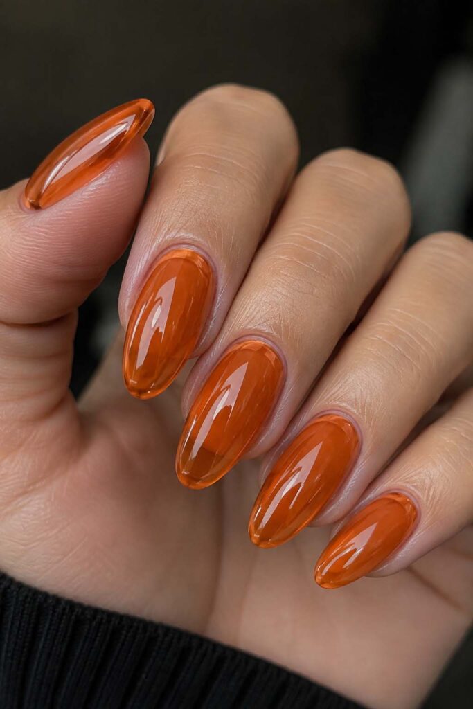 A woman's hand with a translucent orange jelly Halloween manicure