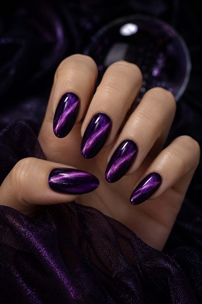 A woman's hand with a Halloween manicure: the purple cat-eye effect