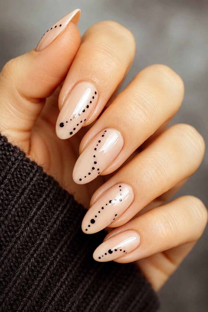 A woman's hand with a Halloween manicure. Black dots arranged in a dotted pattern on a nude background.